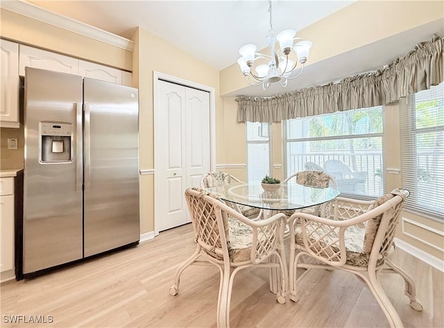 dining room featuring light wood-type flooring, a wainscoted wall, and an inviting chandelier