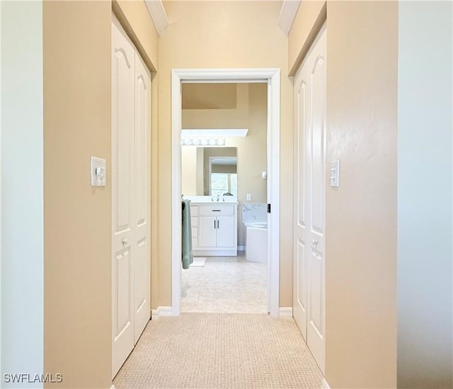 corridor with light carpet and a sink