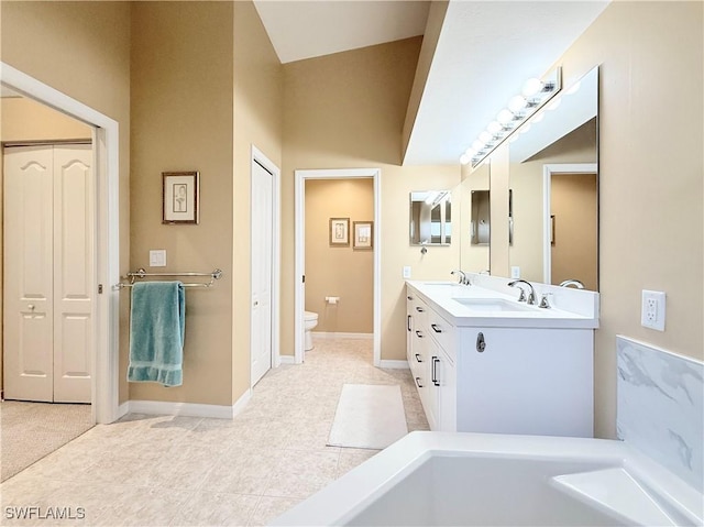 bathroom with double vanity, baseboards, toilet, a sink, and a closet