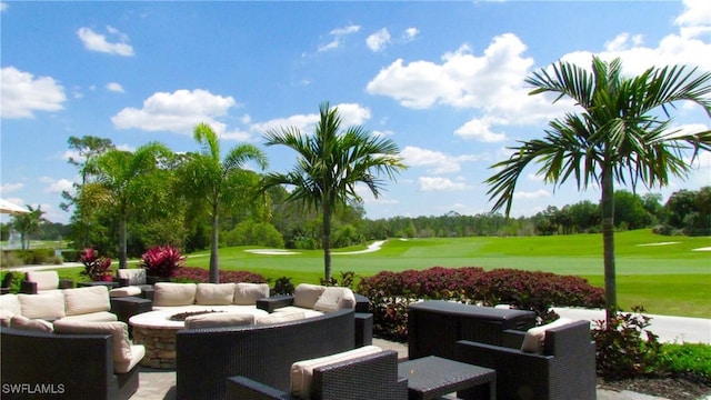 view of property's community featuring a patio, a yard, golf course view, and an outdoor living space with a fire pit