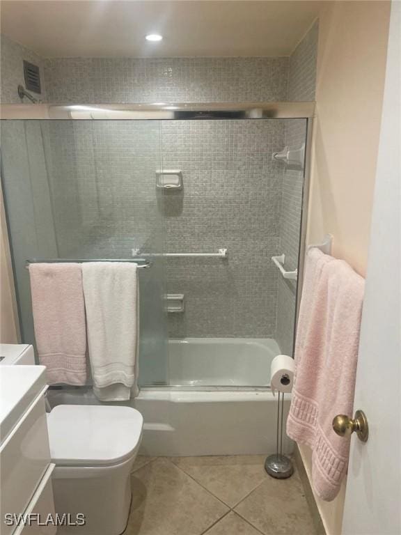 bathroom featuring toilet, visible vents, vanity, combined bath / shower with glass door, and tile patterned floors