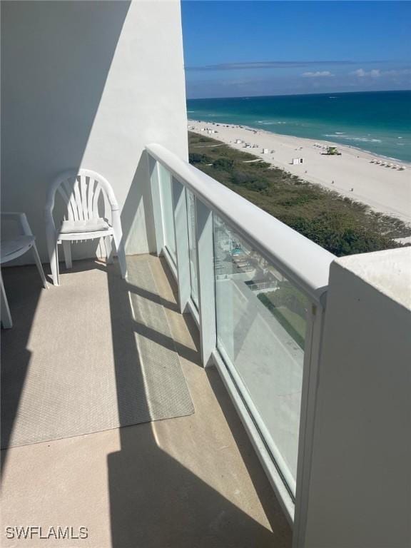 balcony with a water view and a view of the beach