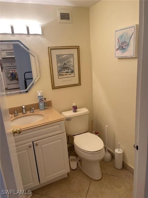 half bathroom featuring visible vents, vanity, toilet, and tile patterned floors