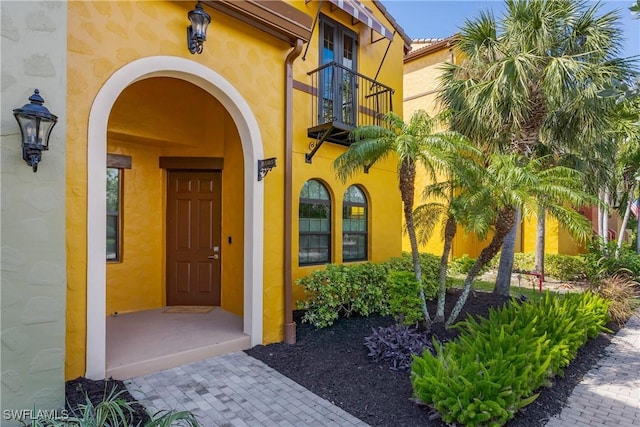 entrance to property with stucco siding and a balcony