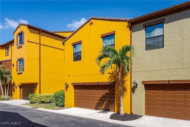 mediterranean / spanish-style house featuring stucco siding, a garage, and a tiled roof