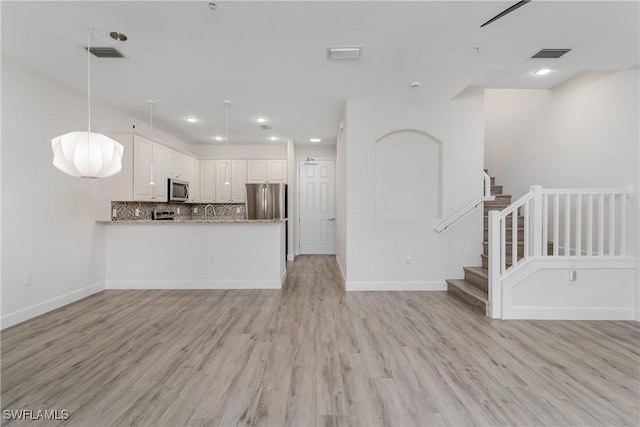 unfurnished living room with visible vents, baseboards, stairs, and light wood-style floors