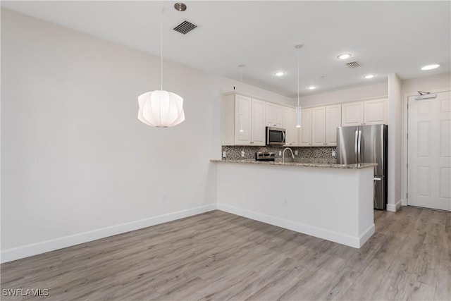 kitchen featuring baseboards, visible vents, stainless steel appliances, light wood-style floors, and tasteful backsplash