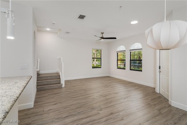 unfurnished living room featuring visible vents, baseboards, stairs, and light wood-style floors