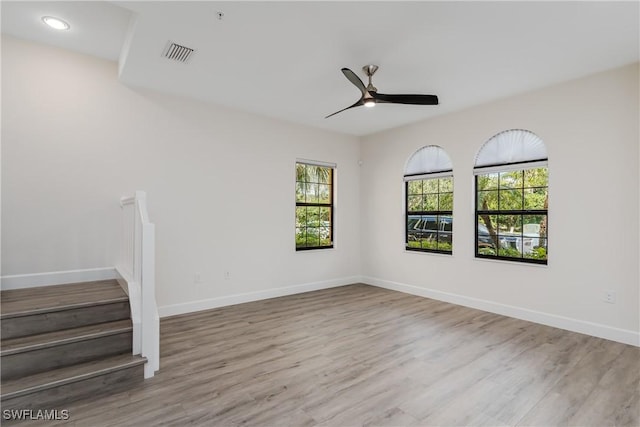 spare room with visible vents, baseboards, wood finished floors, and a ceiling fan