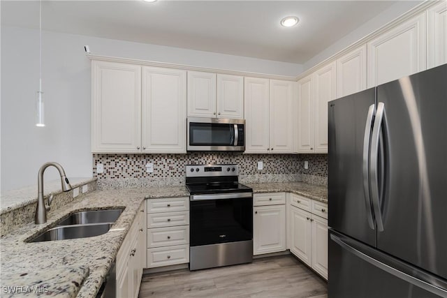 kitchen with decorative backsplash, light wood finished floors, appliances with stainless steel finishes, and a sink