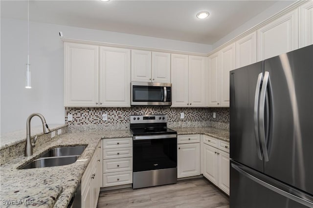 9072 Covina Dr N Unit 5505, Naples, FL 34113 - kitchen featuring appliances with stainless steel finishes, a sink, backsplash, light wood-type flooring, and light stone counters