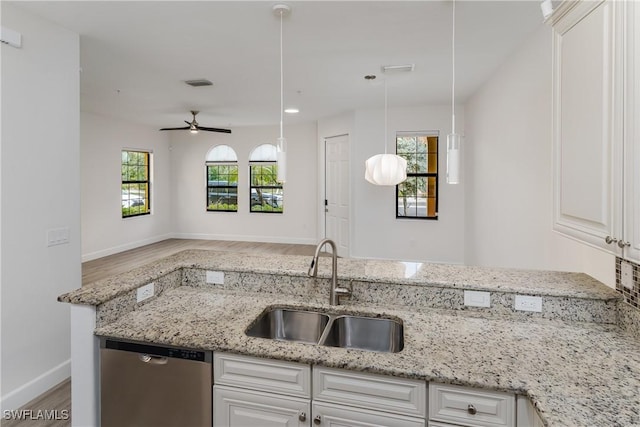 kitchen with visible vents, a sink, light stone counters, wood finished floors, and dishwasher