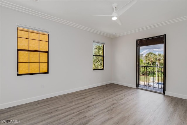 spare room with crown molding, wood finished floors, baseboards, and ceiling fan