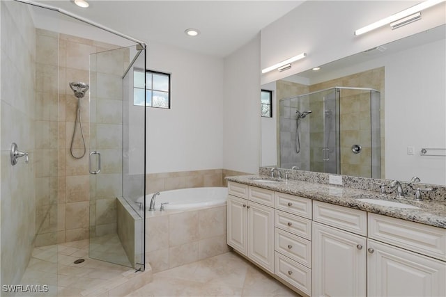 full bath with a bath, a stall shower, double vanity, and a sink