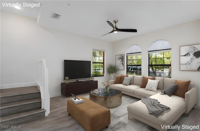 living area featuring visible vents, baseboards, a ceiling fan, and wood finished floors