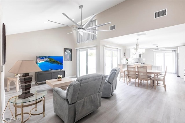 living area with visible vents, a healthy amount of sunlight, ceiling fan with notable chandelier, and light wood-style flooring