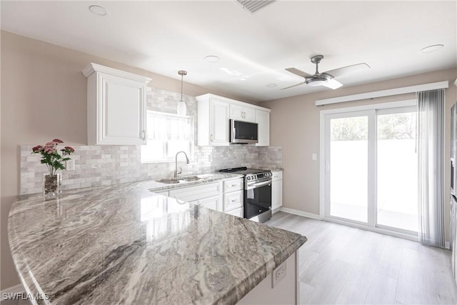 kitchen featuring decorative backsplash, appliances with stainless steel finishes, light stone countertops, white cabinetry, and a sink