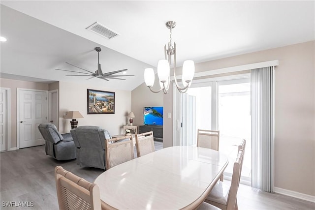 dining space featuring baseboards, visible vents, vaulted ceiling, light wood-type flooring, and ceiling fan with notable chandelier