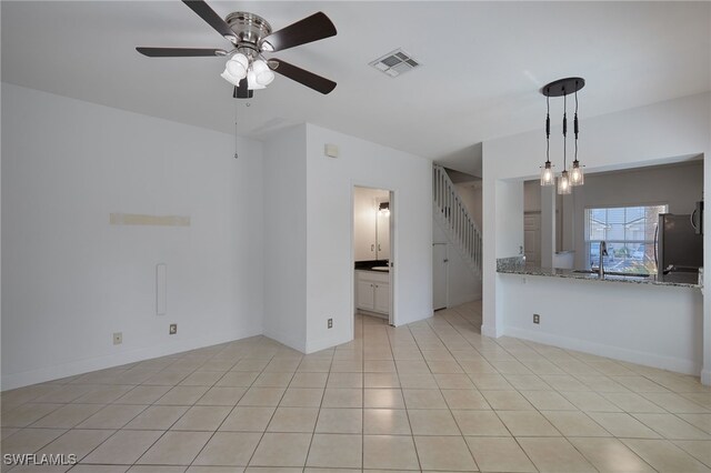 unfurnished living room featuring light tile patterned floors, visible vents, baseboards, ceiling fan, and stairway