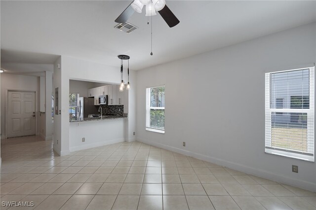 empty room featuring light tile patterned flooring, visible vents, and baseboards