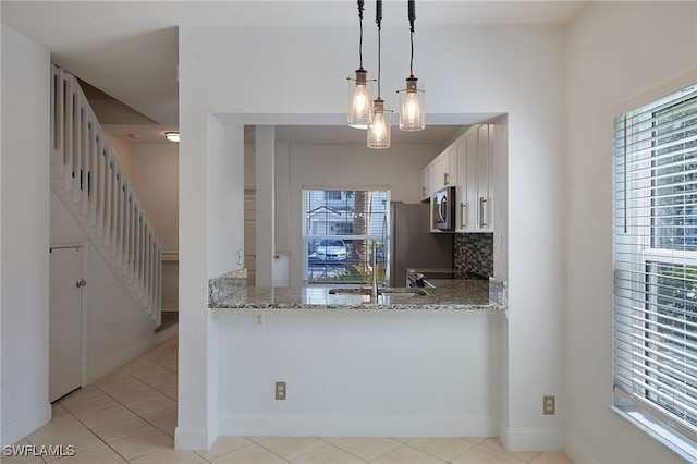 kitchen featuring white cabinetry, tasteful backsplash, stainless steel microwave, and light stone counters