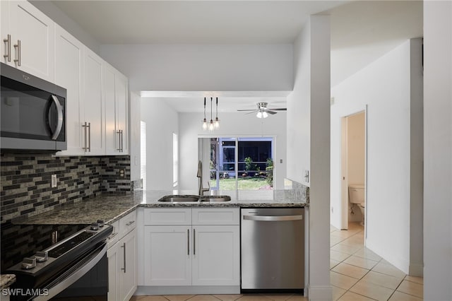 kitchen featuring light stone counters, stainless steel appliances, backsplash, white cabinetry, and a sink