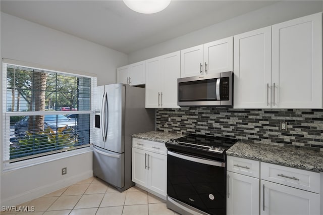 kitchen with stainless steel appliances, white cabinets, light tile patterned flooring, and backsplash