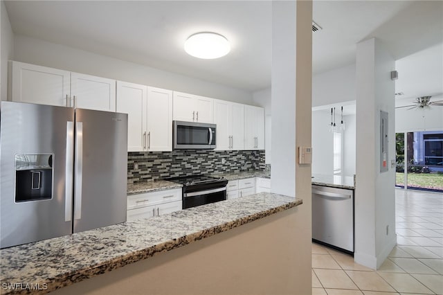 kitchen with light stone countertops, white cabinetry, appliances with stainless steel finishes, and backsplash