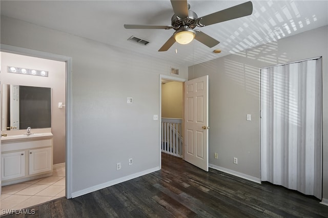 unfurnished bedroom featuring baseboards, visible vents, wood finished floors, and ensuite bathroom