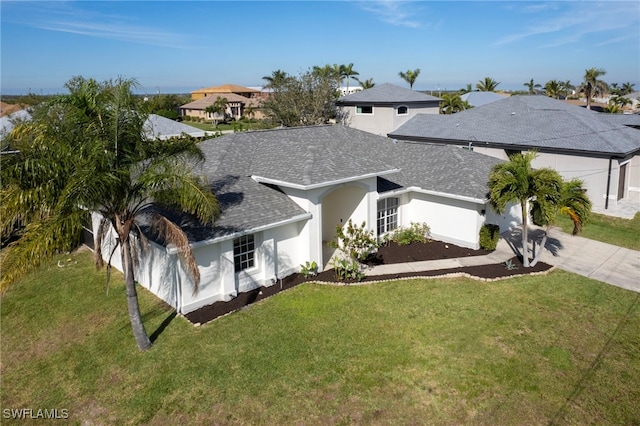 view of front of property featuring stucco siding, a front yard, driveway, and a shingled roof