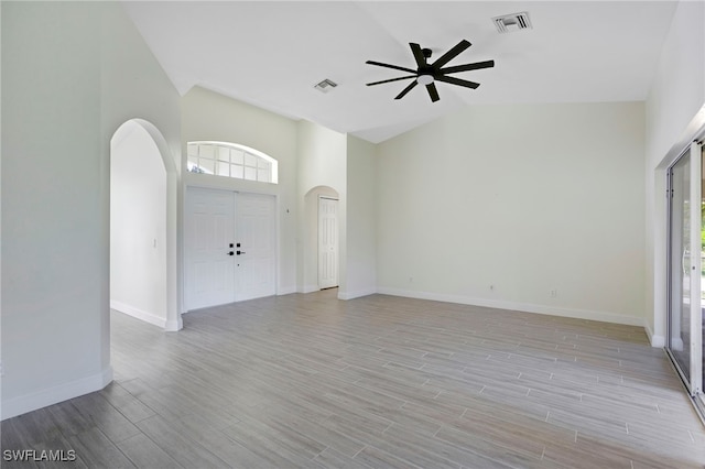 interior space featuring visible vents, arched walkways, light wood-style floors, and a ceiling fan