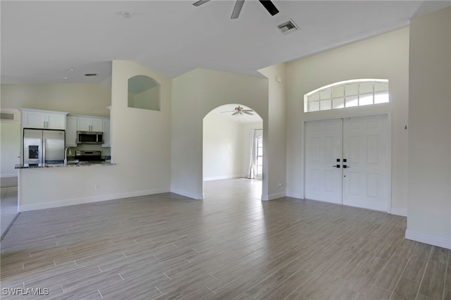 foyer with visible vents, arched walkways, light wood-style floors, and ceiling fan