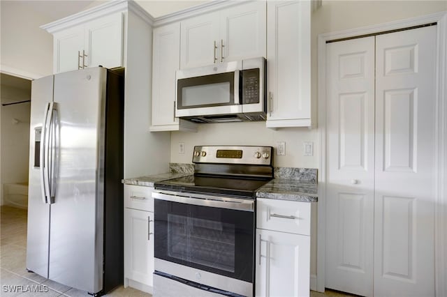 kitchen with light stone counters, light tile patterned floors, white cabinetry, and stainless steel appliances