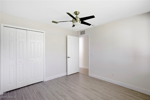 unfurnished bedroom featuring visible vents, baseboards, wood finish floors, a closet, and a ceiling fan