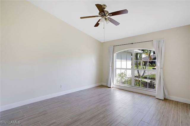 spare room featuring vaulted ceiling, wood finished floors, baseboards, and ceiling fan