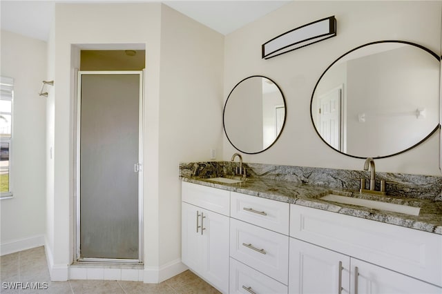 full bath with a sink, a stall shower, double vanity, and tile patterned flooring