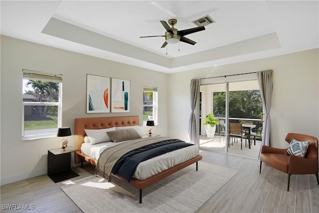 bedroom featuring a raised ceiling, access to outside, multiple windows, and visible vents