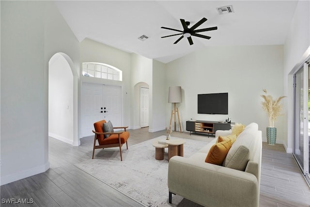 living room with visible vents, arched walkways, and wood finished floors