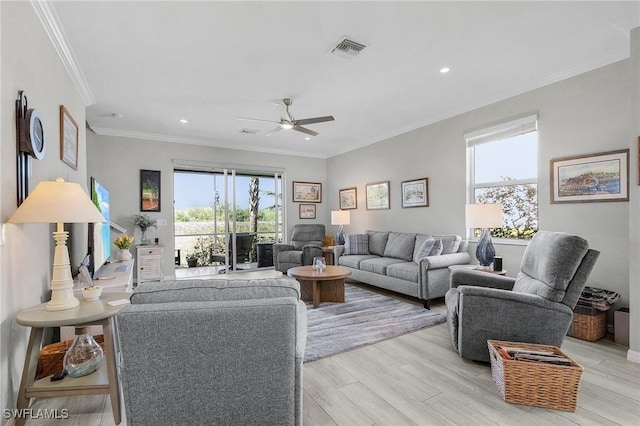 living area with crown molding, light wood-style flooring, plenty of natural light, and visible vents