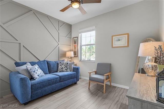 living room with a ceiling fan, baseboards, and light wood-type flooring