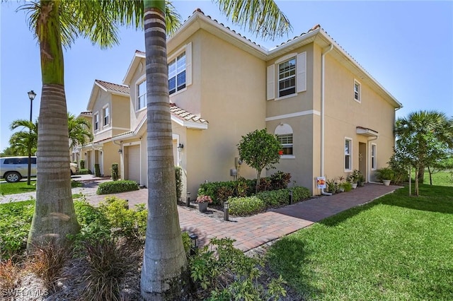 view of side of home with a garage, stucco siding, decorative driveway, and a yard