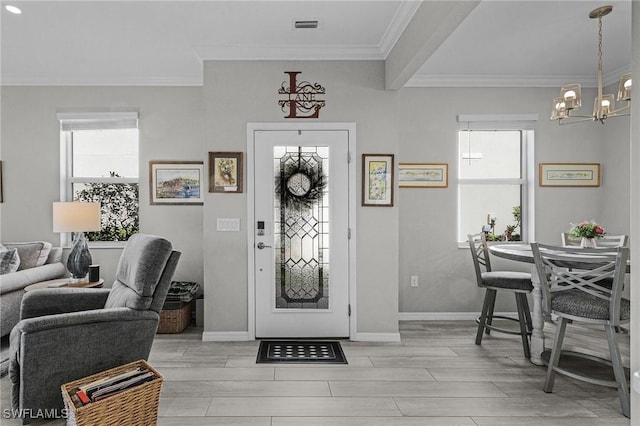 entrance foyer with visible vents, crown molding, baseboards, wood finish floors, and an inviting chandelier