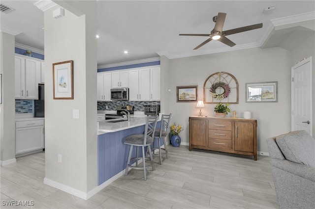 kitchen with visible vents, ornamental molding, white cabinets, appliances with stainless steel finishes, and a kitchen breakfast bar