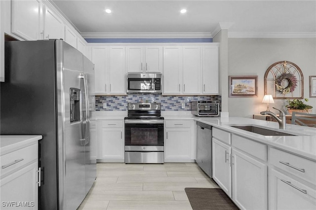 kitchen with appliances with stainless steel finishes, white cabinetry, crown molding, and a sink