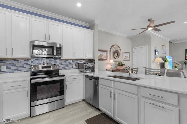 kitchen with a sink, stainless steel appliances, light countertops, crown molding, and tasteful backsplash