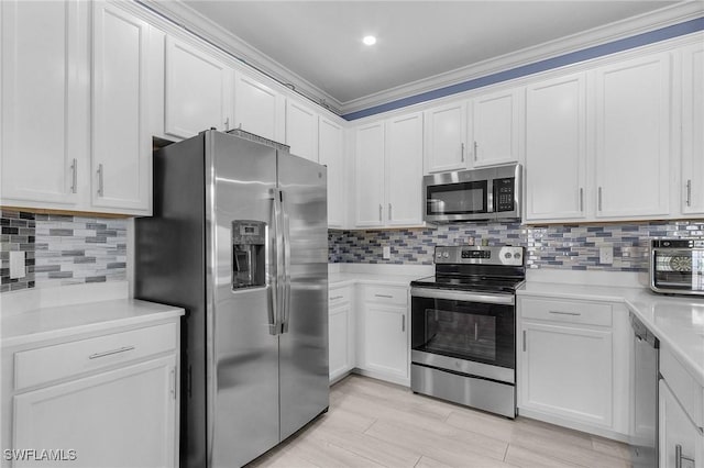 kitchen with tasteful backsplash, white cabinets, appliances with stainless steel finishes, and light countertops