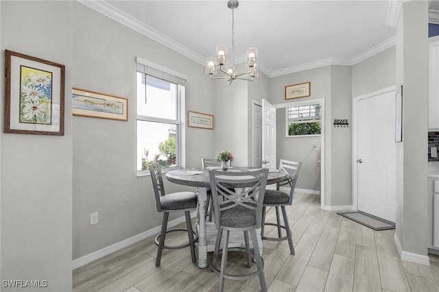 dining room with ornamental molding, an inviting chandelier, light wood-style floors, and baseboards