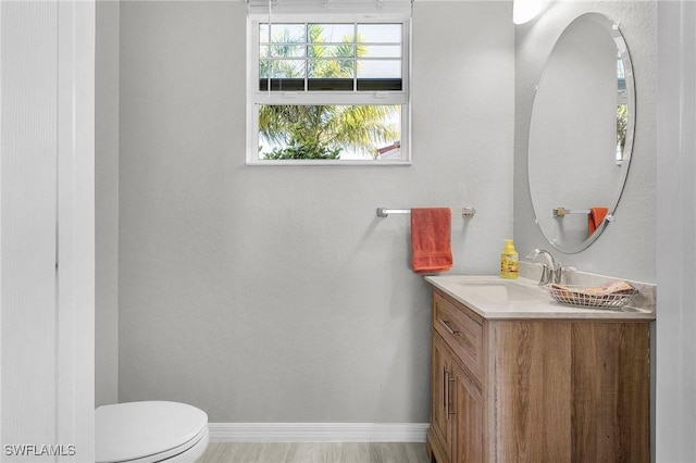 bathroom with toilet, vanity, and baseboards