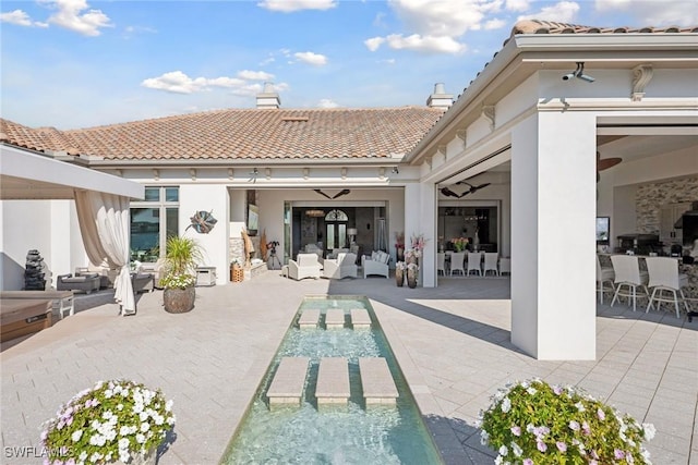 rear view of house featuring a patio area, outdoor dining space, stucco siding, and a chimney