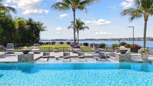 view of pool with a patio, fence, and a water view